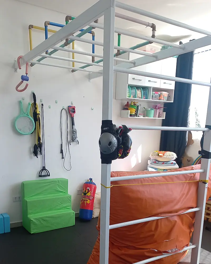 Sala de psicomotricidade do Espaço Daphine Santana, com estrutura de escalar, degraus de espuma e materiais de estimulação